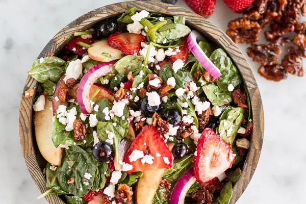Mixed berry salad with strawberry balsamic dressing in a wooden bowl.