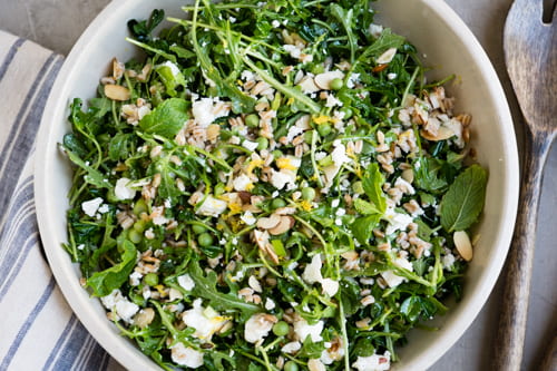 arugula and pea shoot salad in a bowl with feta and almonds