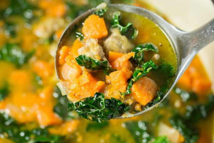 A ladle of Sausage and Sweet Potato Soup with Kale