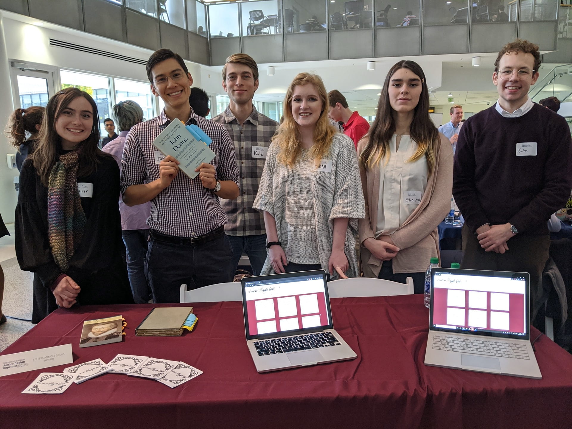 Students standing in front of table with computers ad paper at an academic expo
